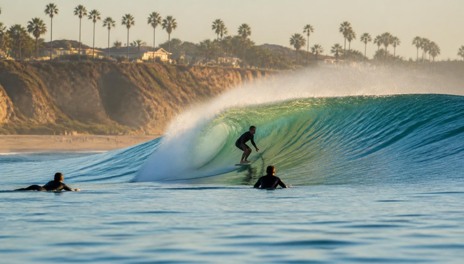 Glassy late-summer wave peeling along the San Diego coast at sunrise with surfers in the lineup